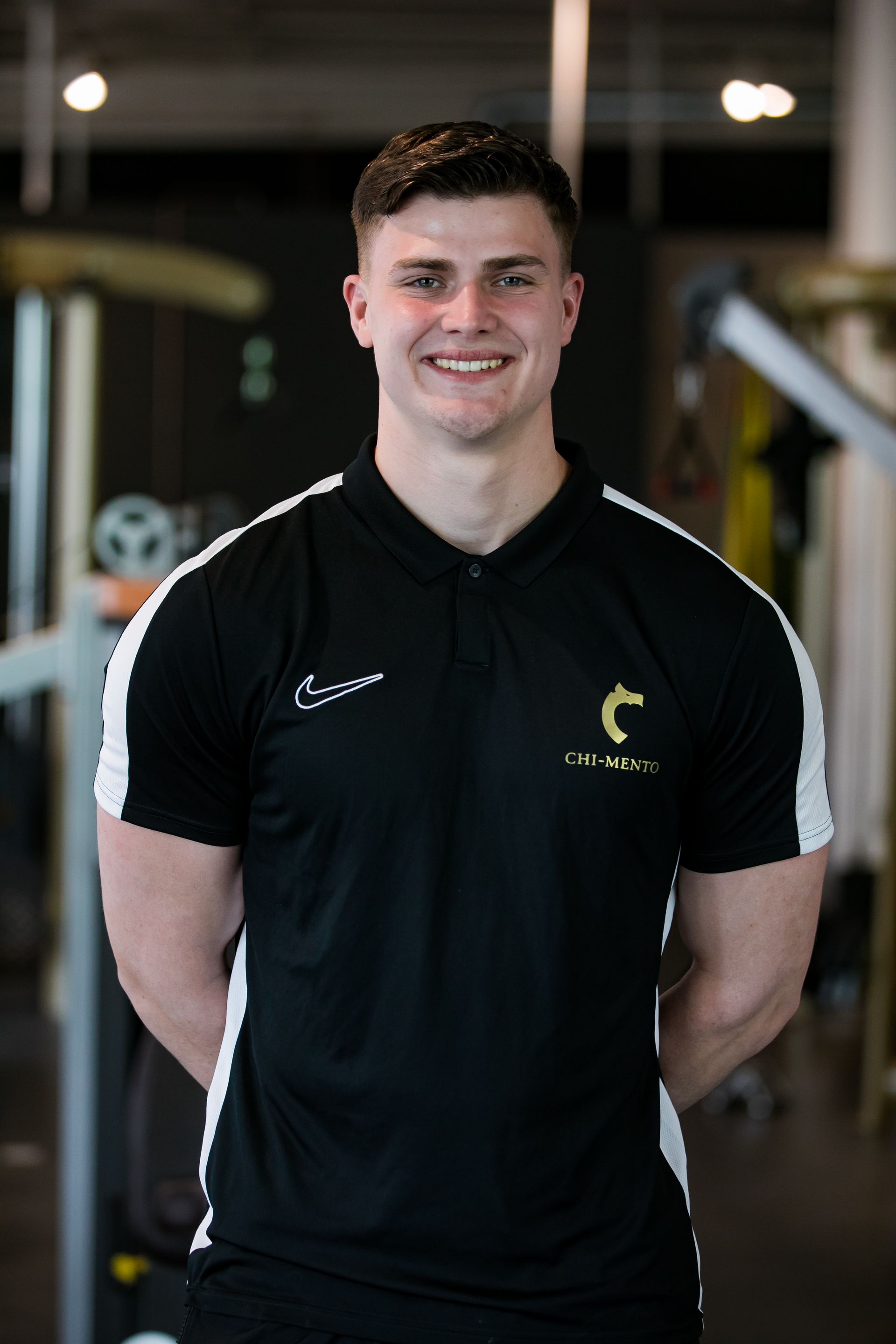 Een jonge man in een zwart shirt lacht in een sportschool.