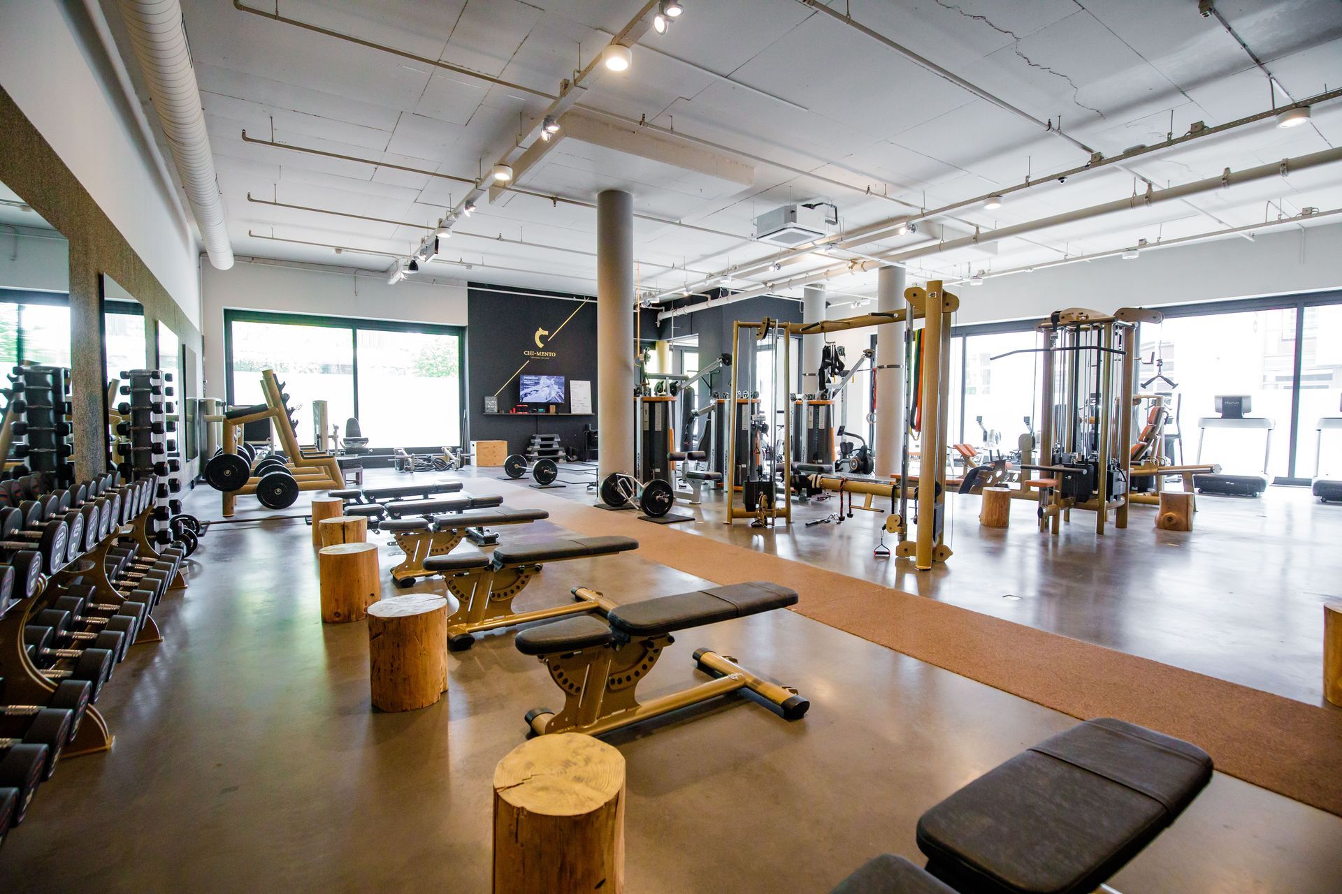 Een grote fitnessruimte vol met veel fitnessapparatuur en banken.