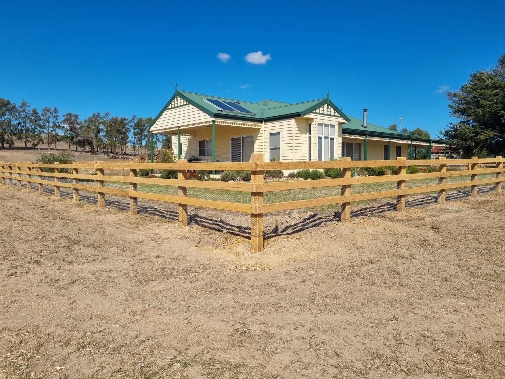 A House With A Green Roof And A Wooden Fence In Front Of It — Ettles Rural Fencing in Alfredton, VIC