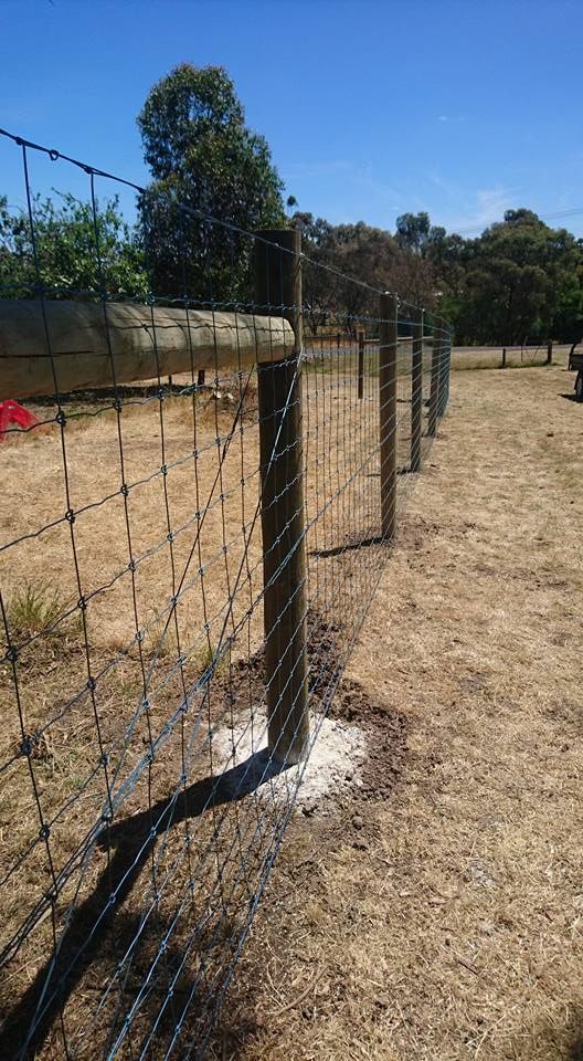 A Barbed Wire Fence With a Wooden Post in the Middle of a Field — Ettles Rural Fencing in Alfredton, VIC