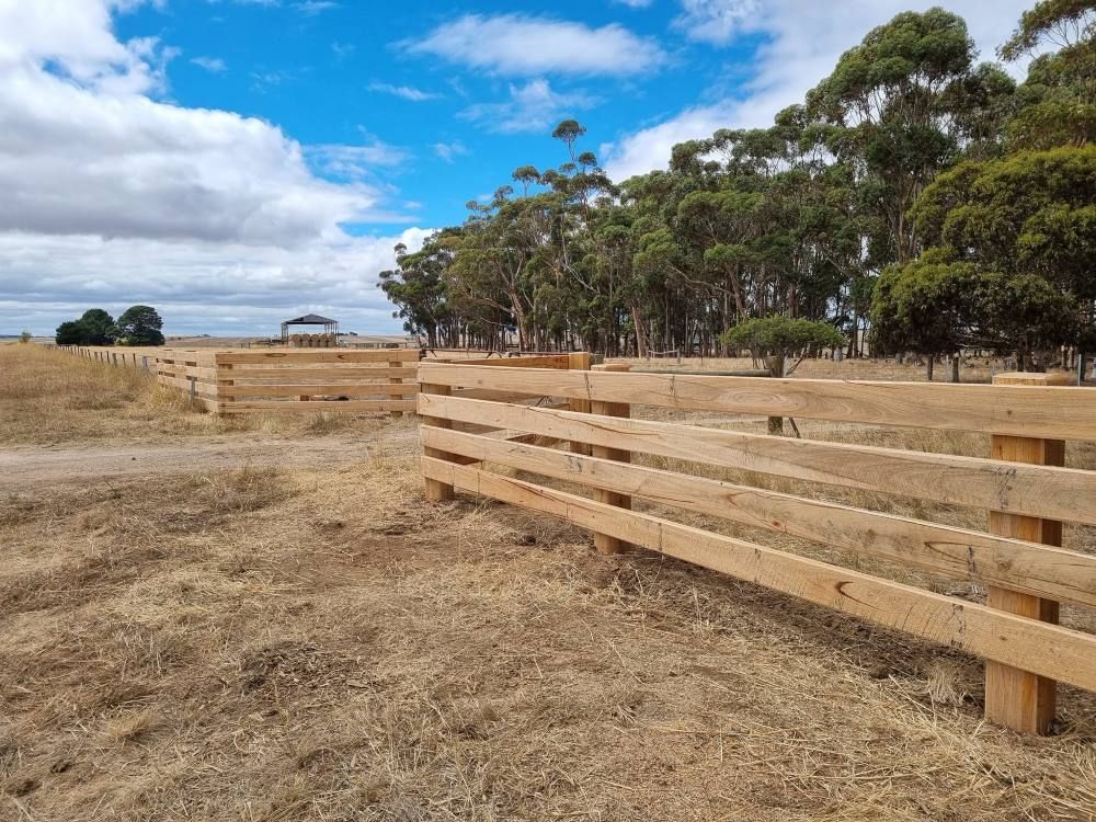 A Wooden Fence In A Field With Trees In The Background — Ettles Rural Fencing in Alfredton, VIC