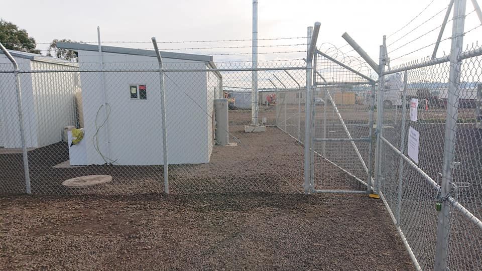 A Chain Link Fence Is Surrounding A White Building — Ettles Rural Fencing in Alfredton, VIC