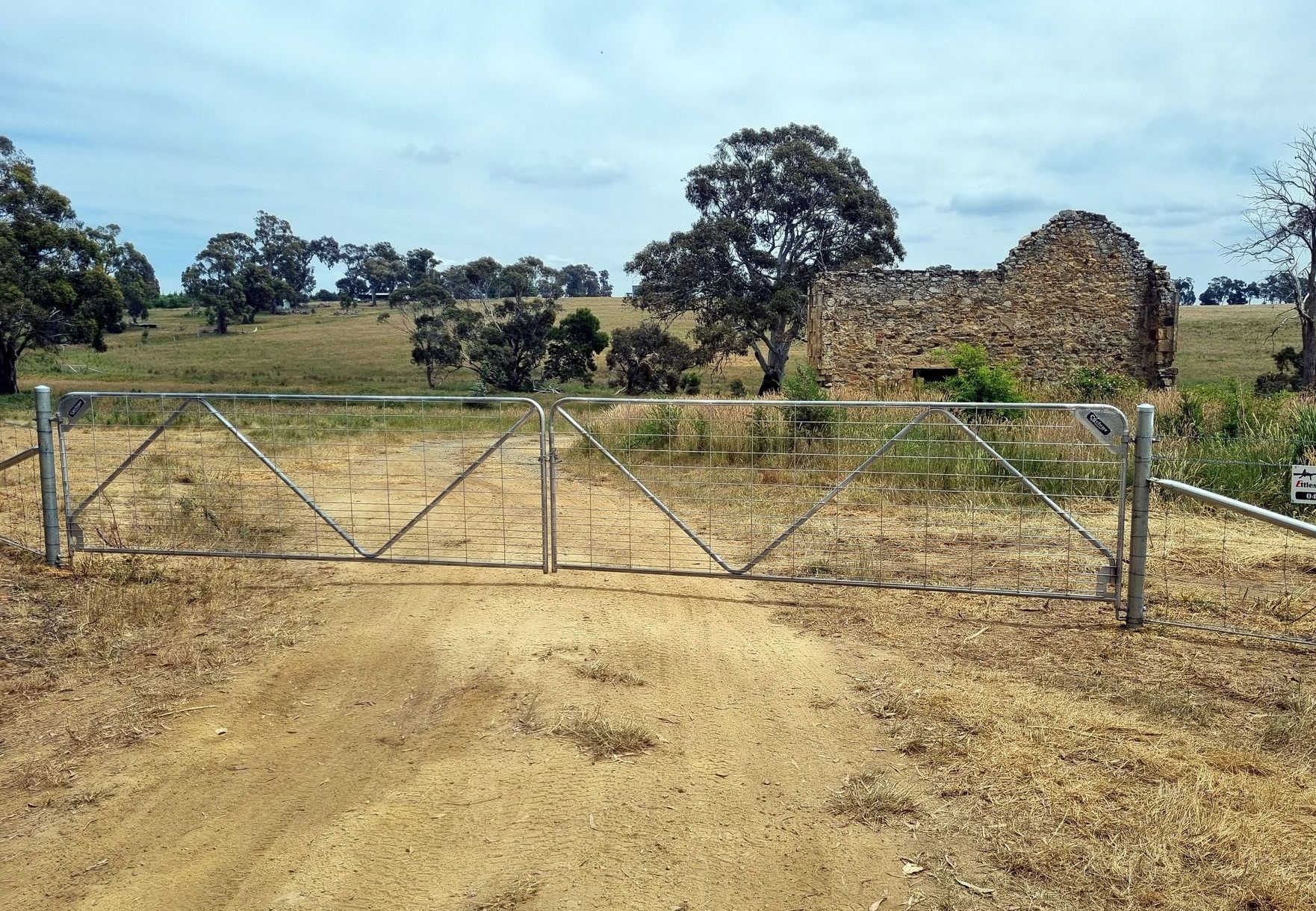A Wooden Fence Is In Front Of A House — Ettles Rural Fencing in Alfredton, VIC