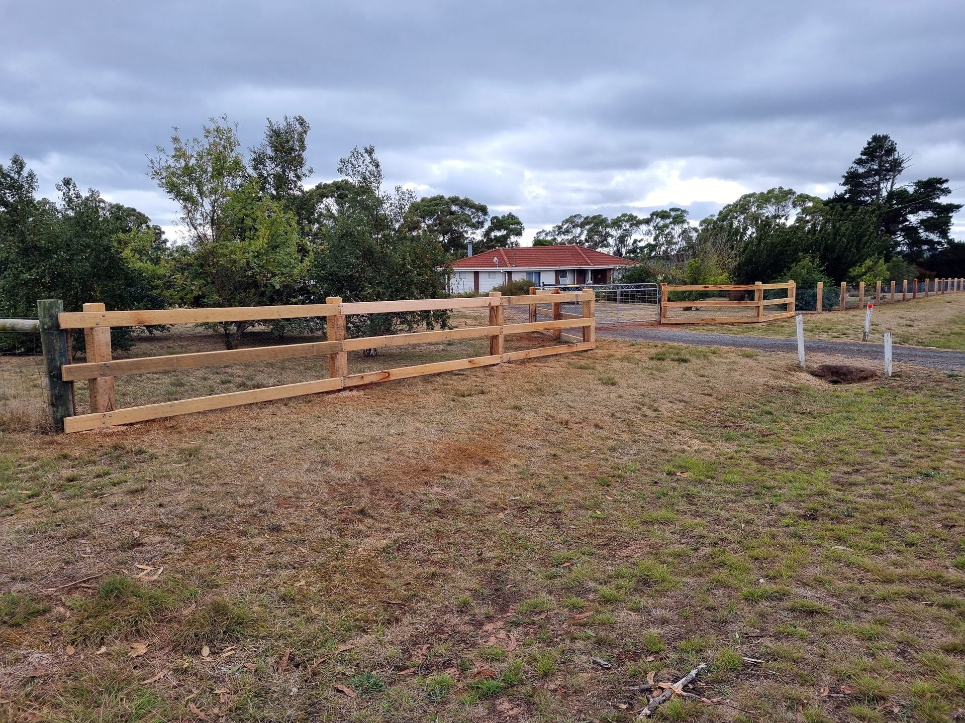 A Black Wooden Fence is Surrounding a Dirt Field — Ettles Rural Fencing in Alfredton, VIC
