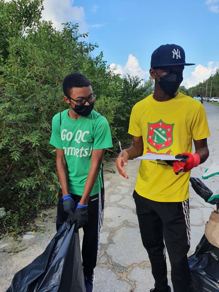 Two young men wearing masks and gloves collect trash