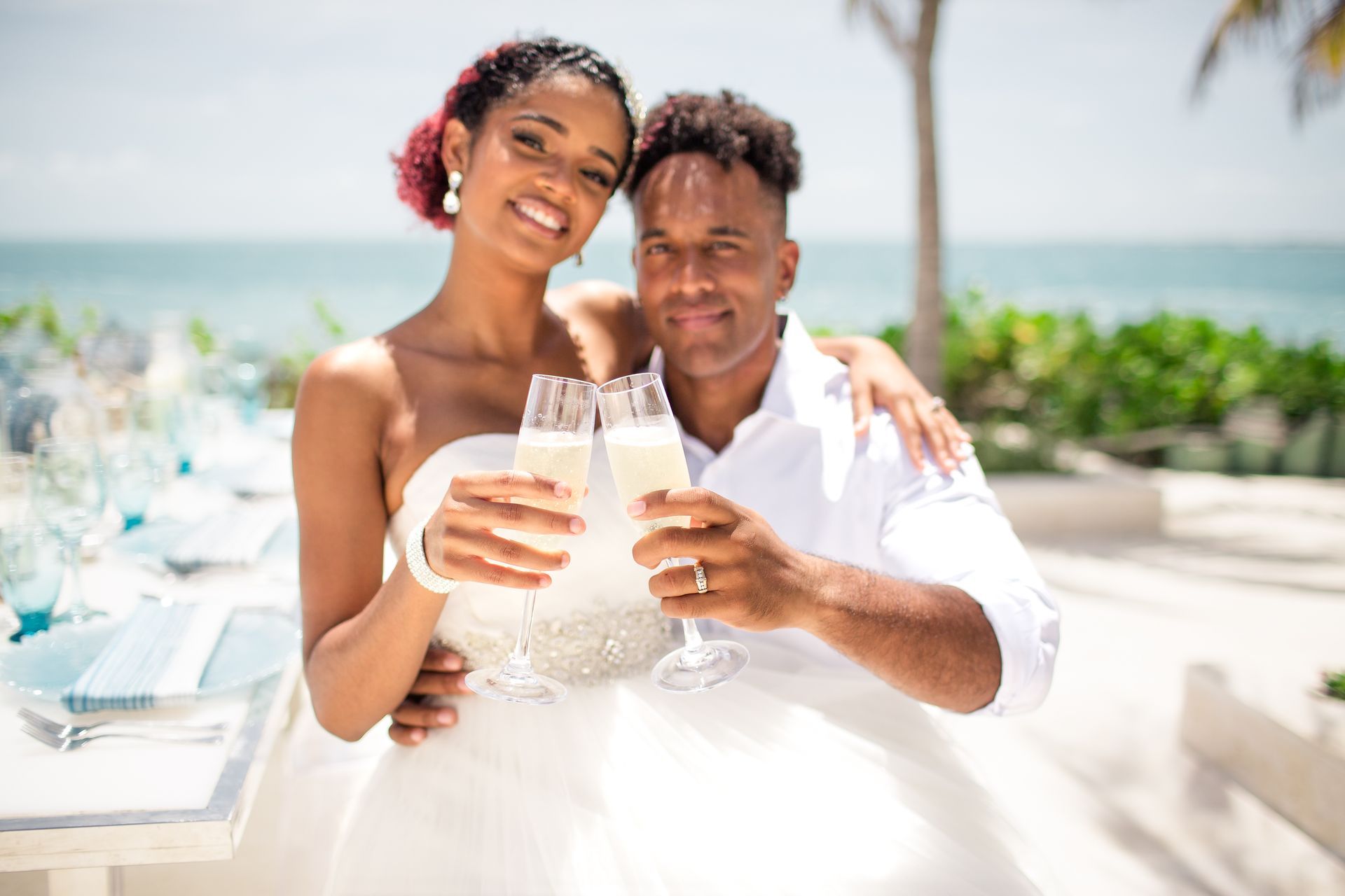 Couple toasting champagne at an outdoor wedding by the ocean.
