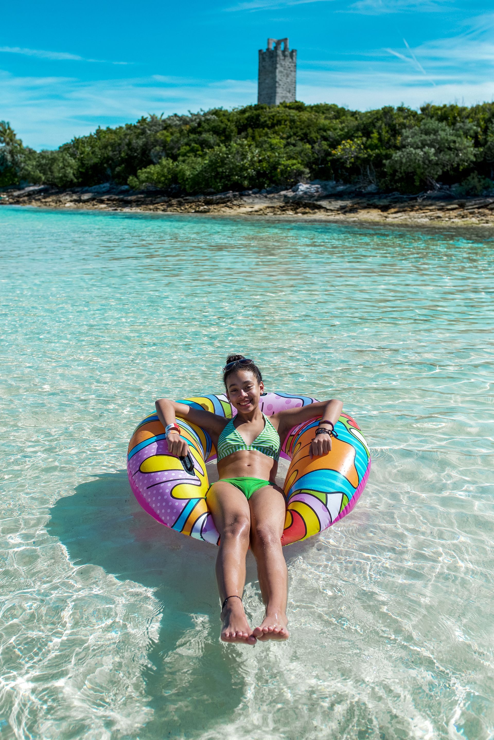 Woman in bikini relaxes in a colorful inflatable ring in clear turquoise water