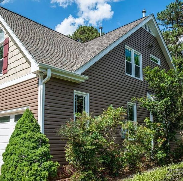 A brown house with a gray roof and white trim