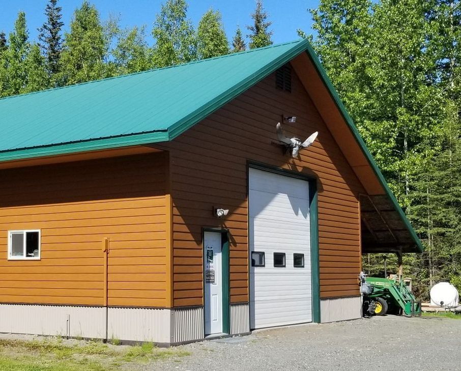 A large wooden building with a green roof is surrounded by trees.