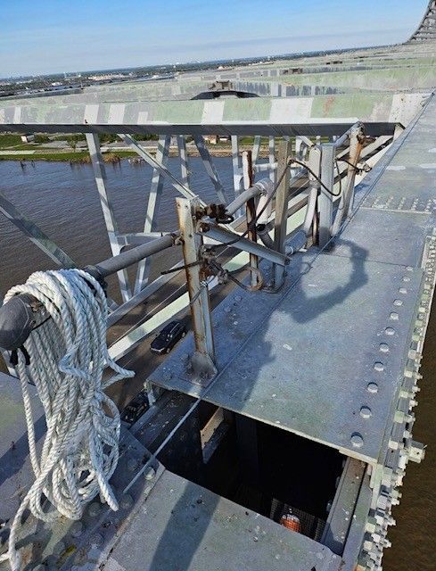 A rope is hanging from the side of a bridge over a body of water