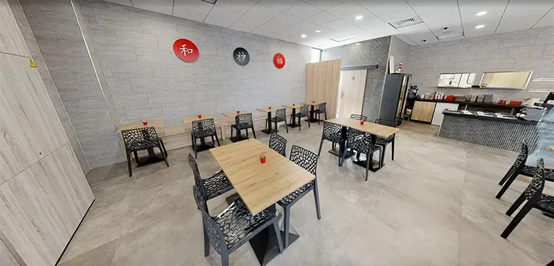 Intérieur d'un restaurant avec tables, chaises et décorations sur un mur de briques claires.