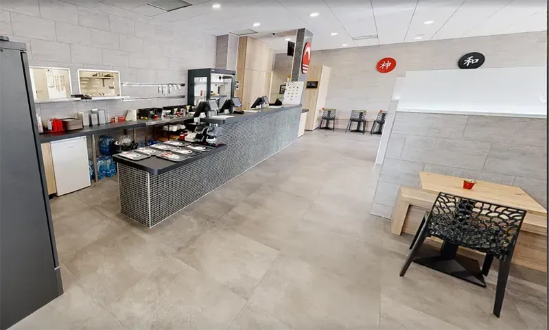 Intérieur d'un établissement de restauration moderne avec comptoir, tables et chaises.