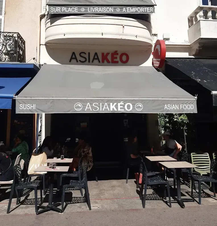 Extérieur du restaurant AsiaKéo avec tables en terrasse, auvent et enseigne indiquant la présence de sushis et de plats asiatiques.