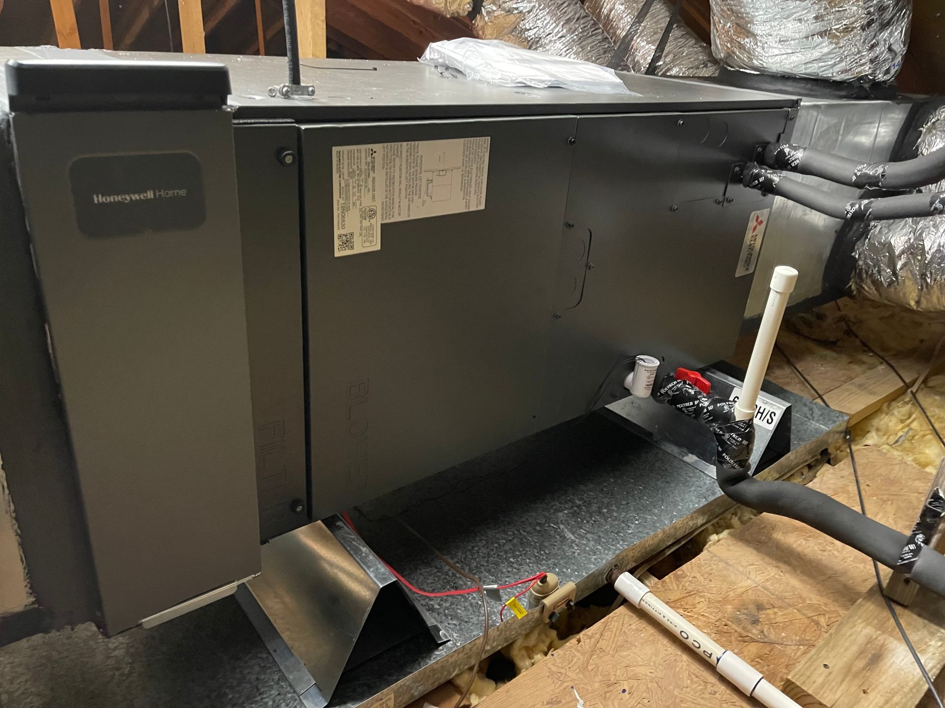 HVAC unit in an attic with ductwork, piping, and electrical components.