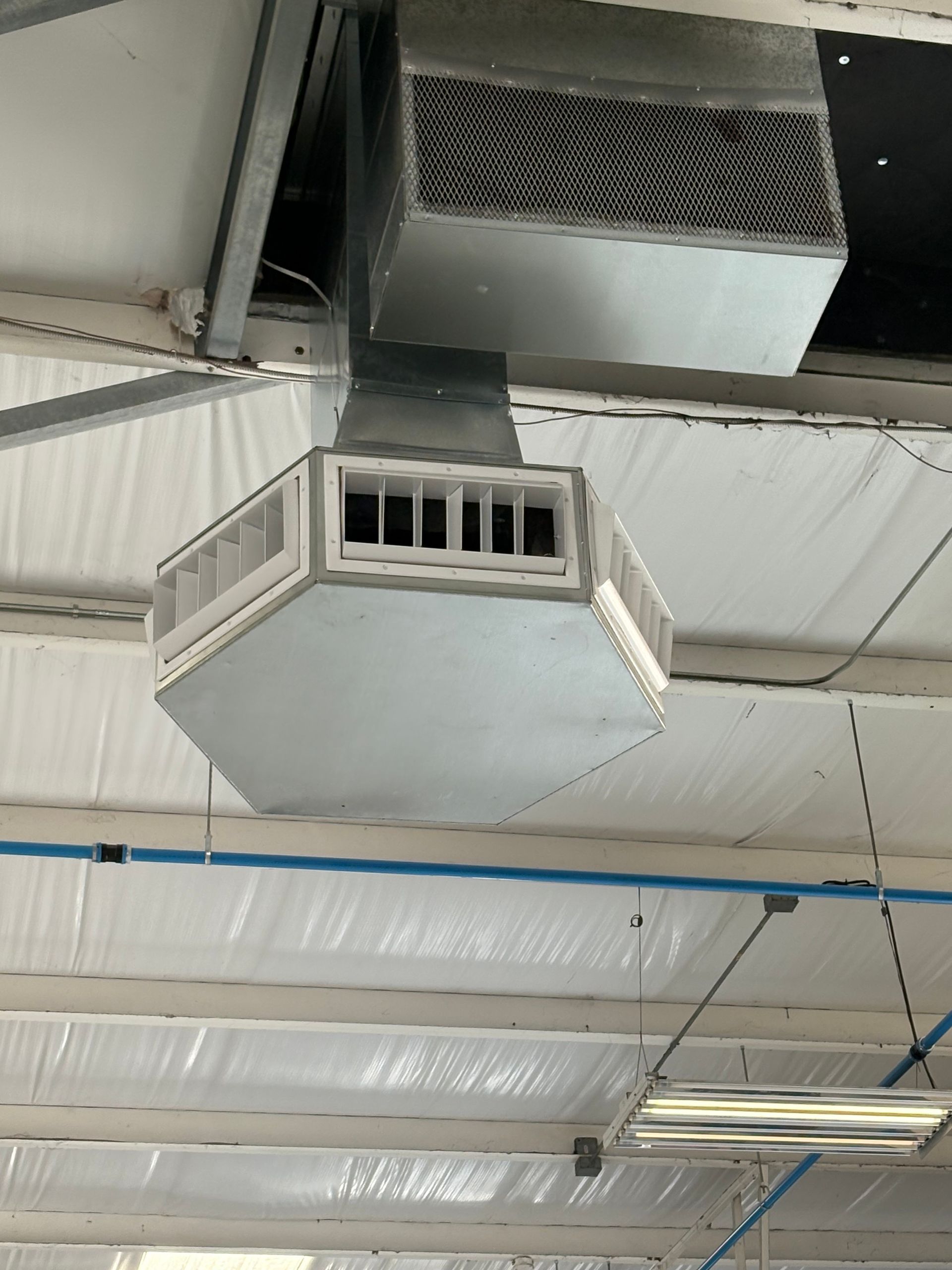 HVAC air vent in a commercial building ceiling, with silver metal ductwork and vents.