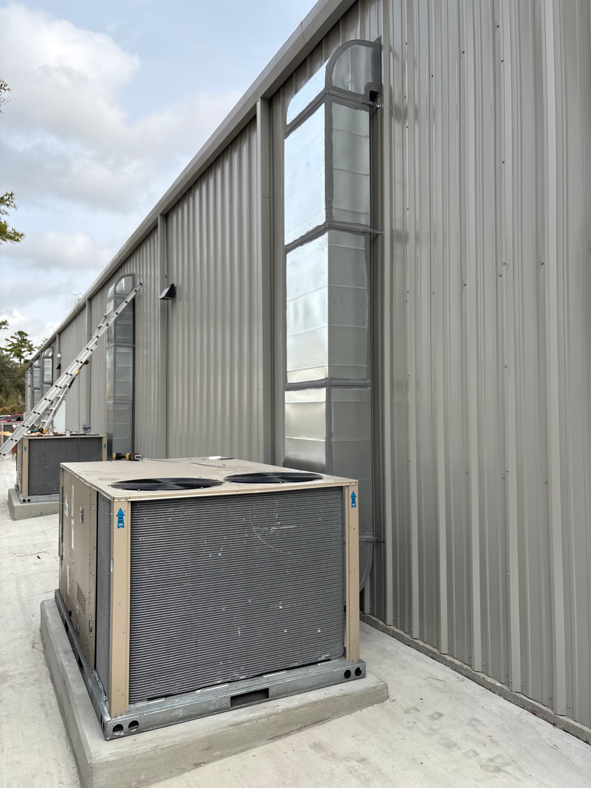 Gray electrical box attached to a corrugated metal building; open vent showing interior.