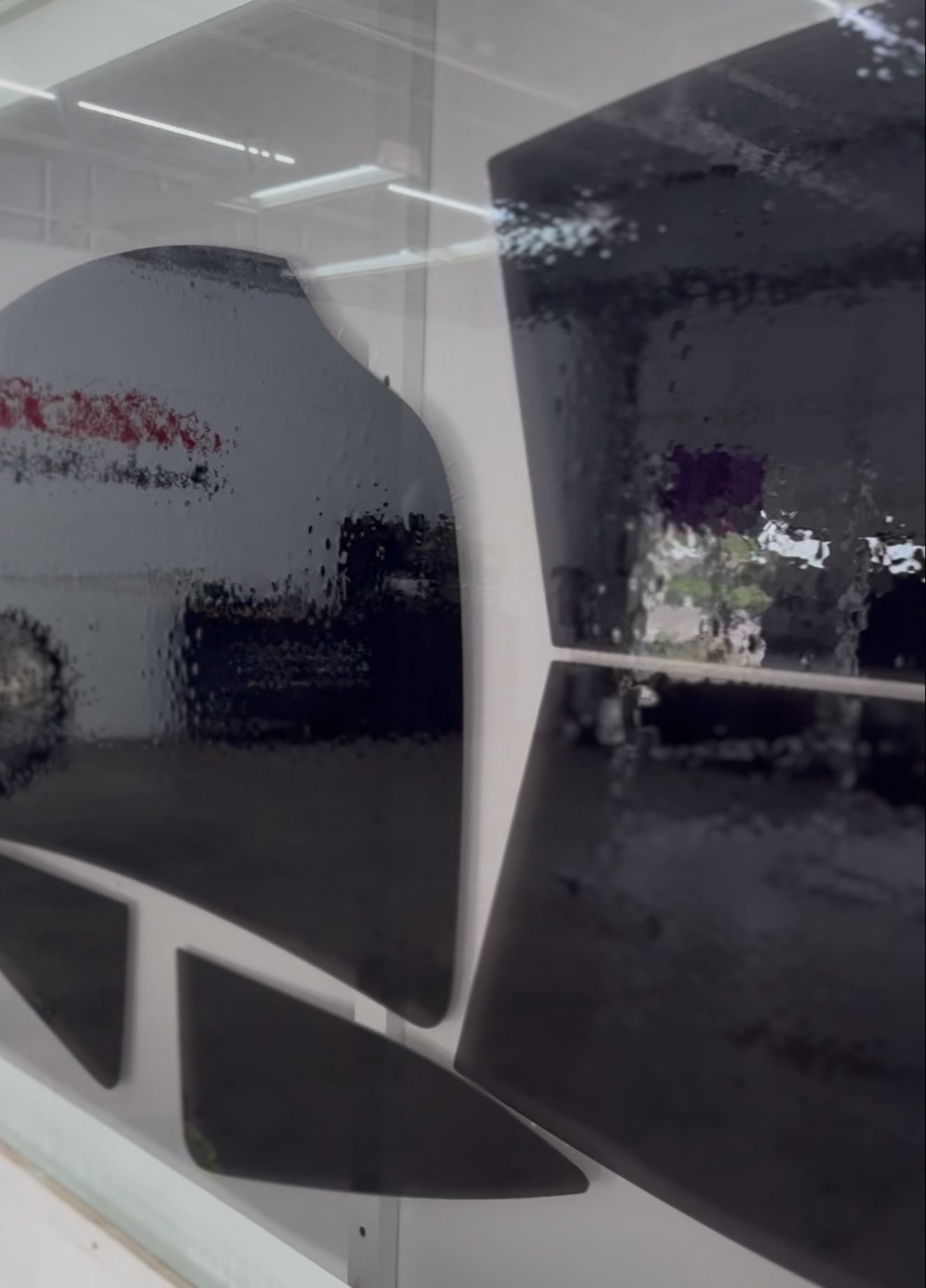 Black tinted window, reflecting a blurry exterior scene, including a car and building.