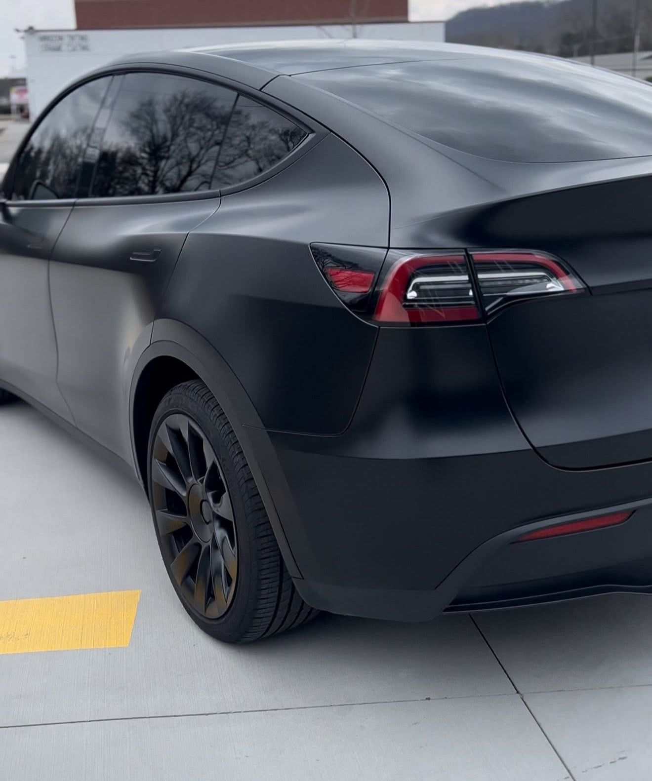Black Tesla Model Y, matte finish, parked outdoors.