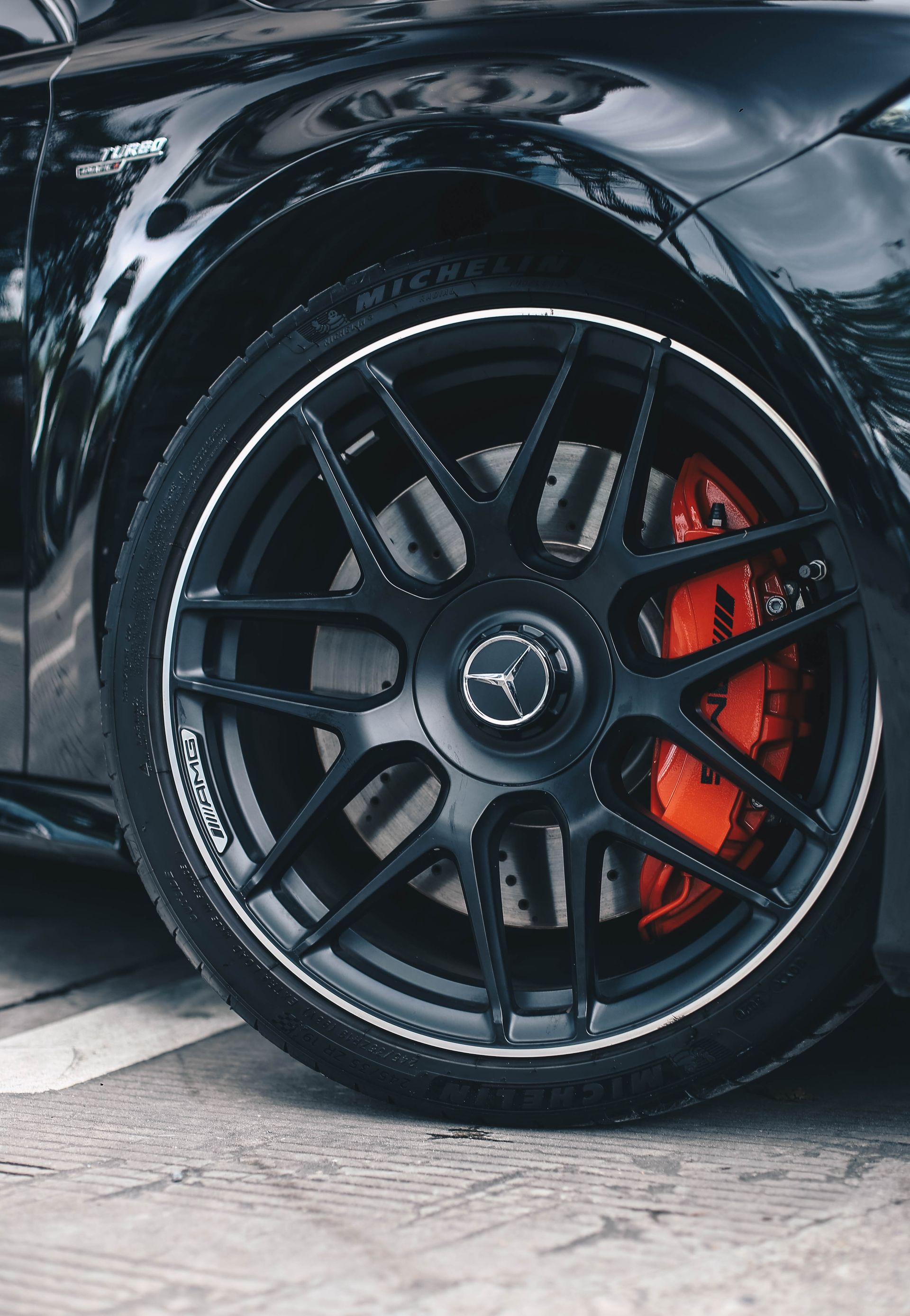 Black Mercedes-Benz car wheel with black rim, red brake calipers, and a silver Mercedes logo.