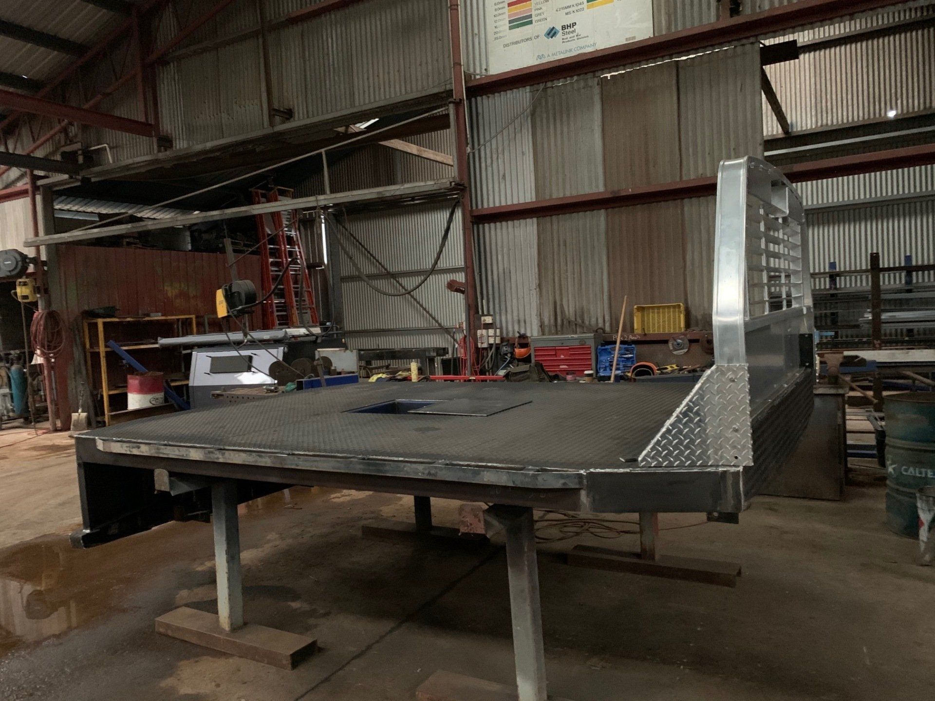 A truck bed is sitting on top of a wooden table in a warehouse.