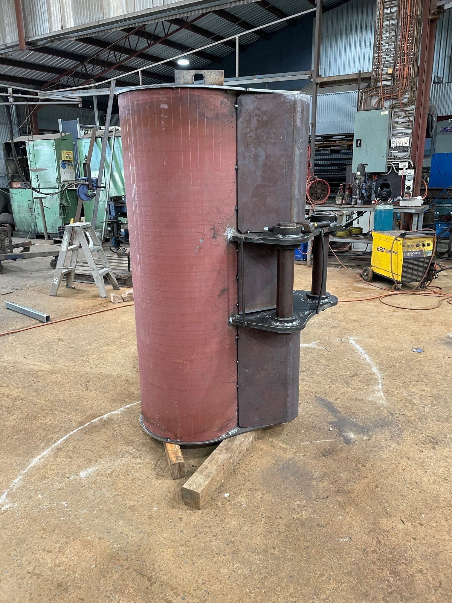 A large metal cylinder is sitting on the ground in a factory.