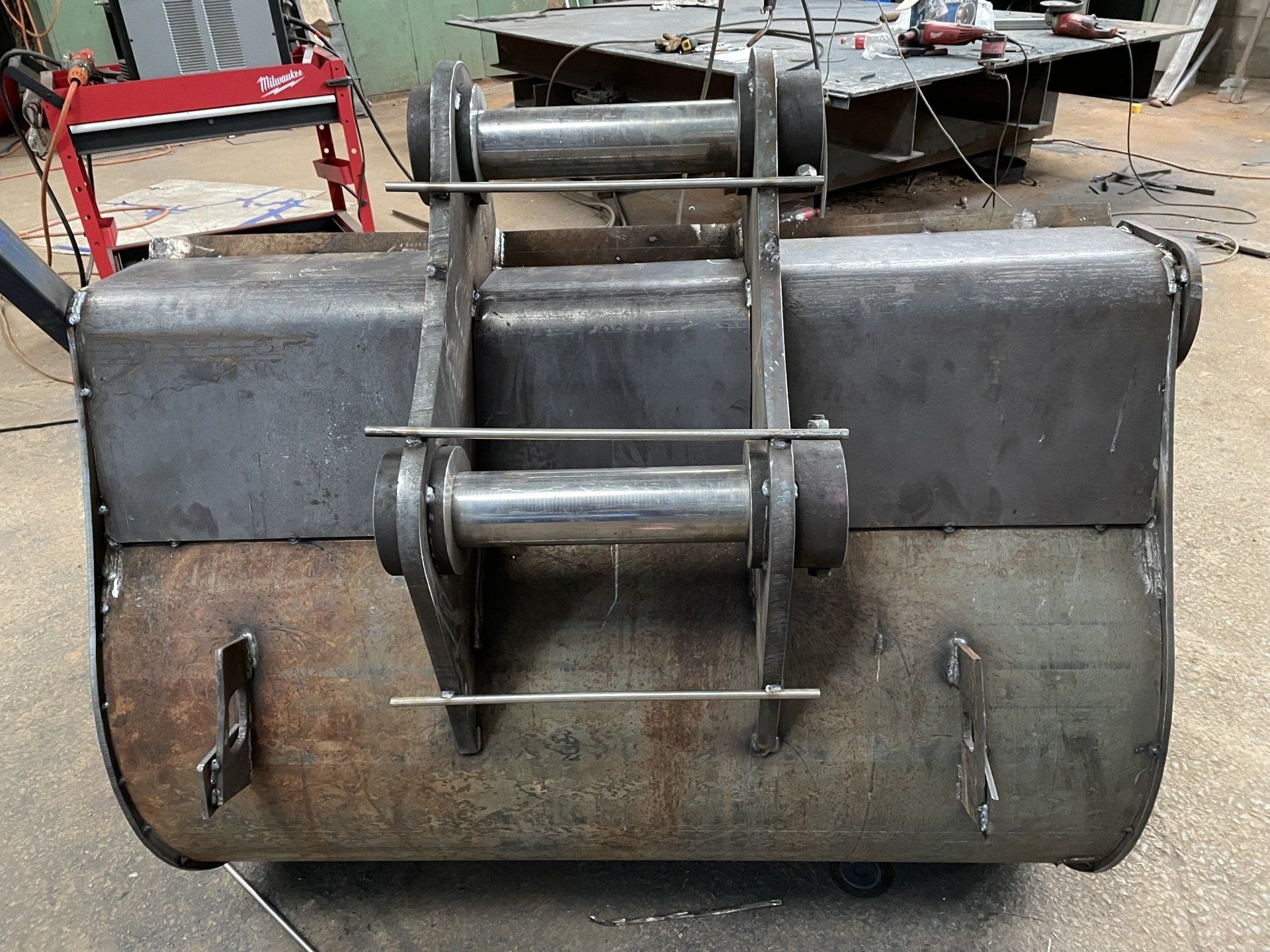 A metal bucket is sitting on the ground in a workshop.