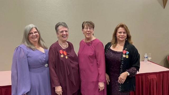 A group of people shaking hands in front of a tall ship