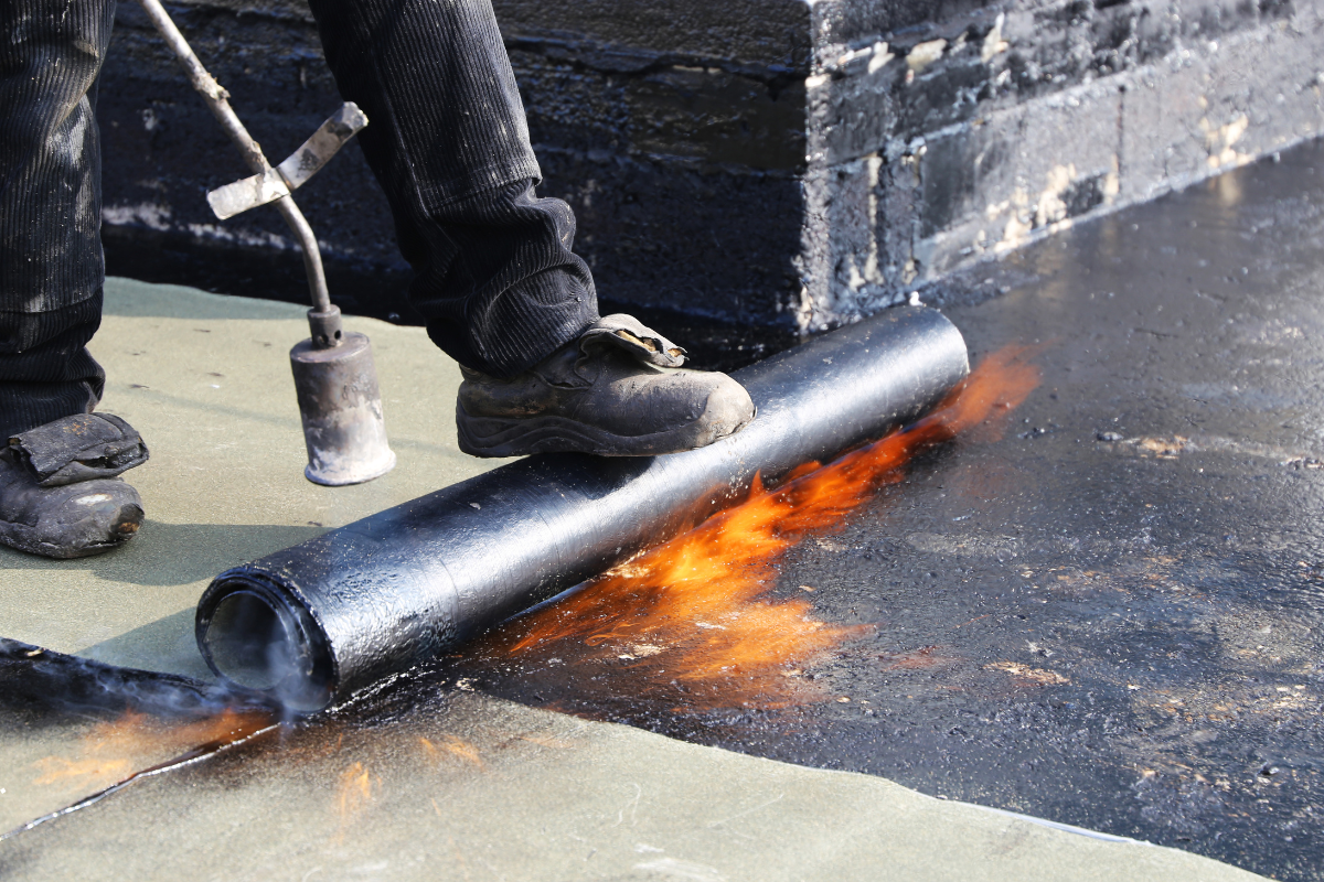 Worker installing a waterproofing membrane with a heat torch