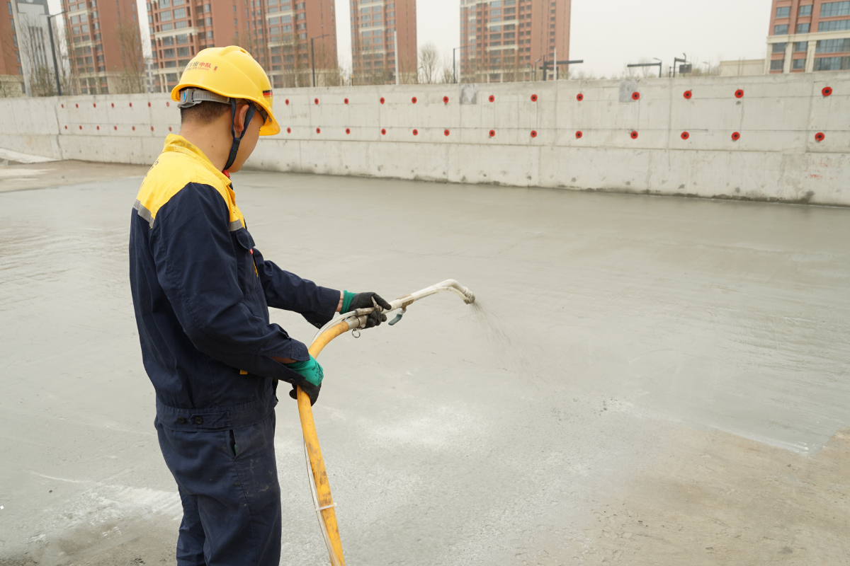 Worker applying cementitious waterproofing system to a concrete surface