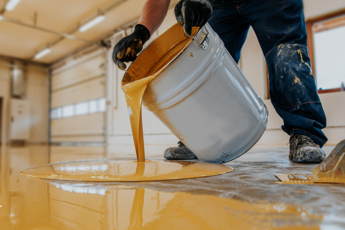 Worker pouring epoxy coating for industrial flooring