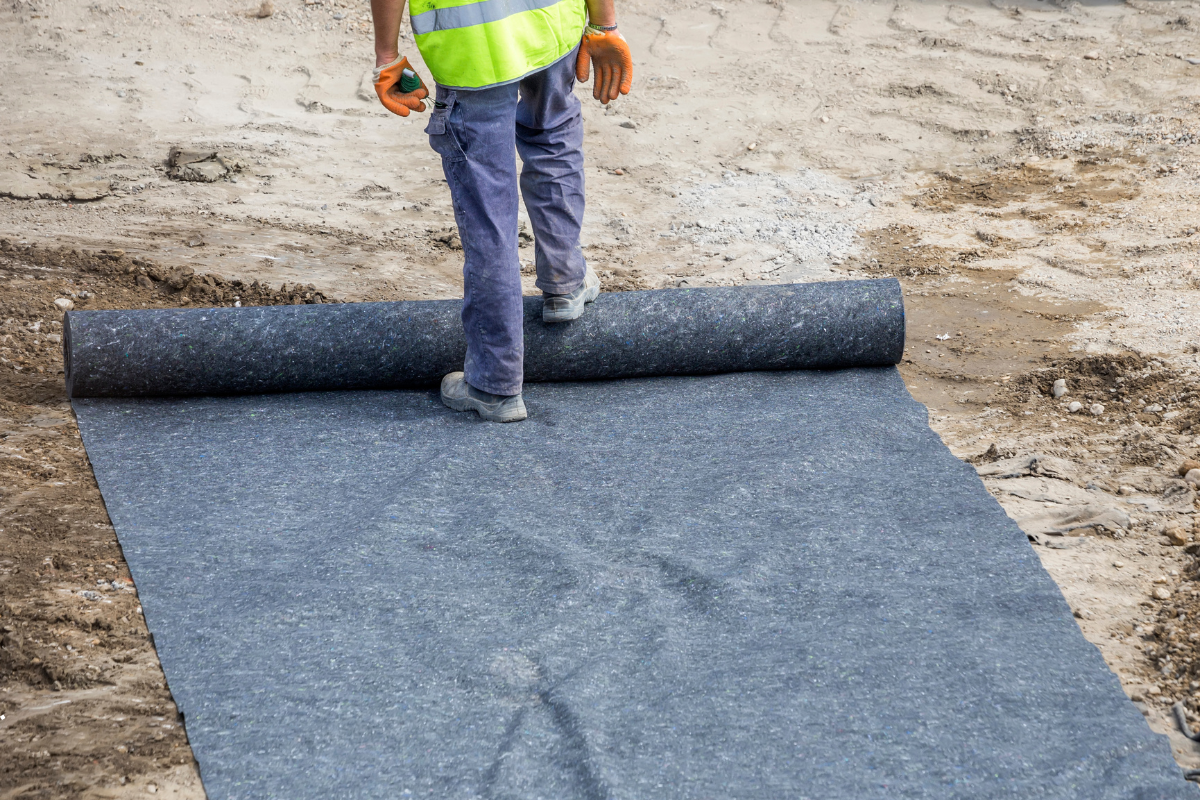 Worker laying geotextile fabric for soil stabilization