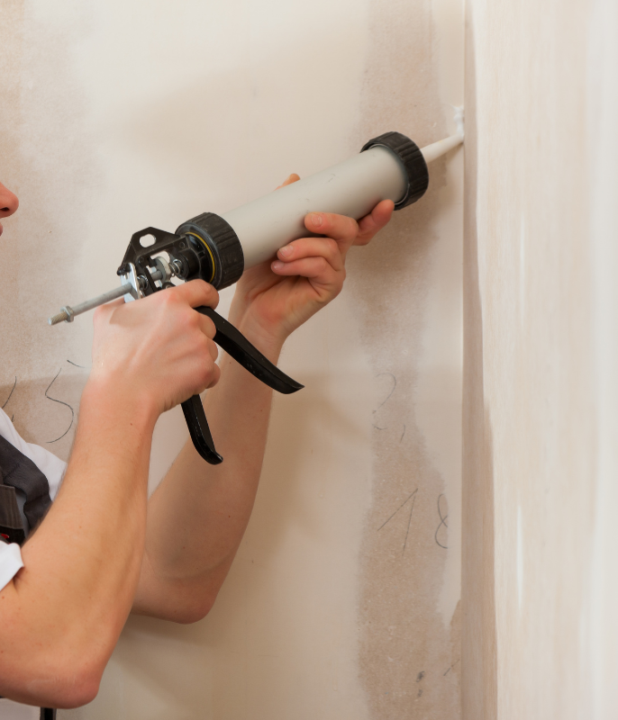 Worker using a grouting gun for wall repair