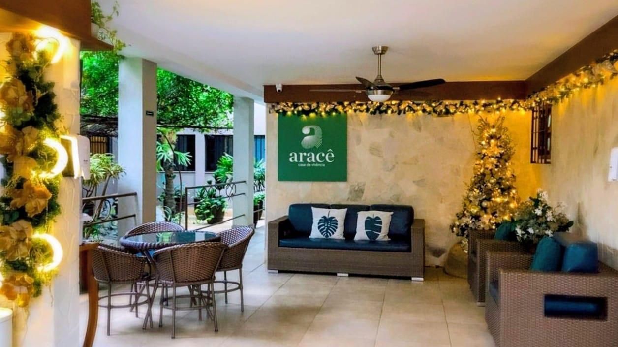 Área de estar externa com sofá, cadeiras e luzes decorativas.