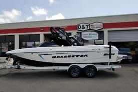 A white Malibu Wakesetter motorboat on a boat trailer parked in front of a building with a D&T sign.
