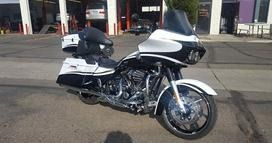 A black and white Harley-Davidson touring motorcycle parked outdoors in front of a service garage.