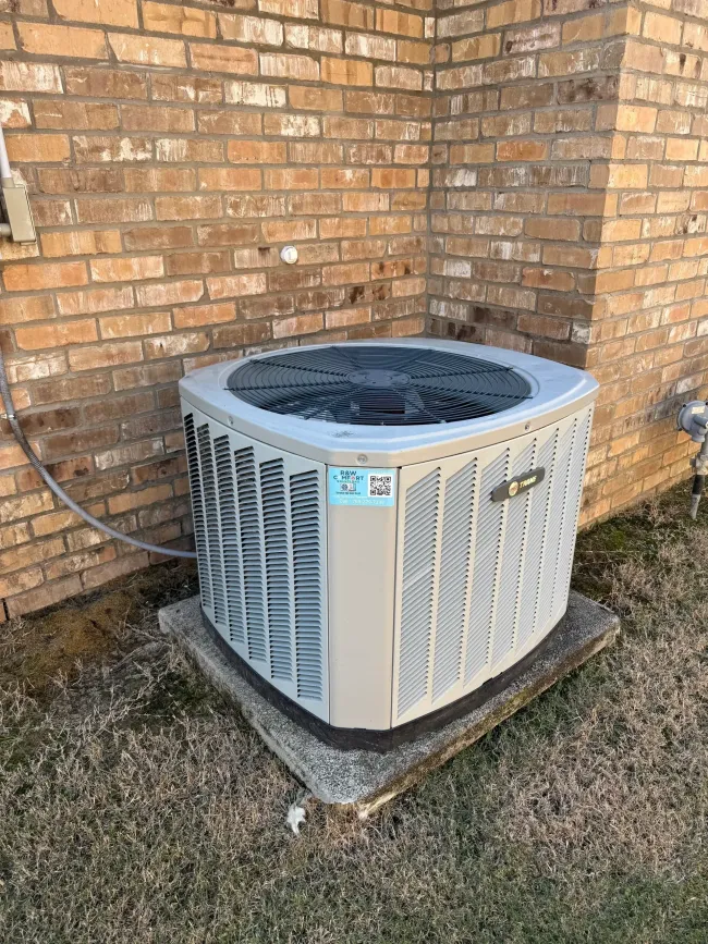 Brick house side yard with two outdoor AC units on a green lawn next to a paved walkway