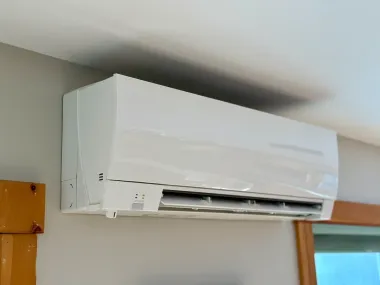White wall-mounted air conditioner above a window in a room