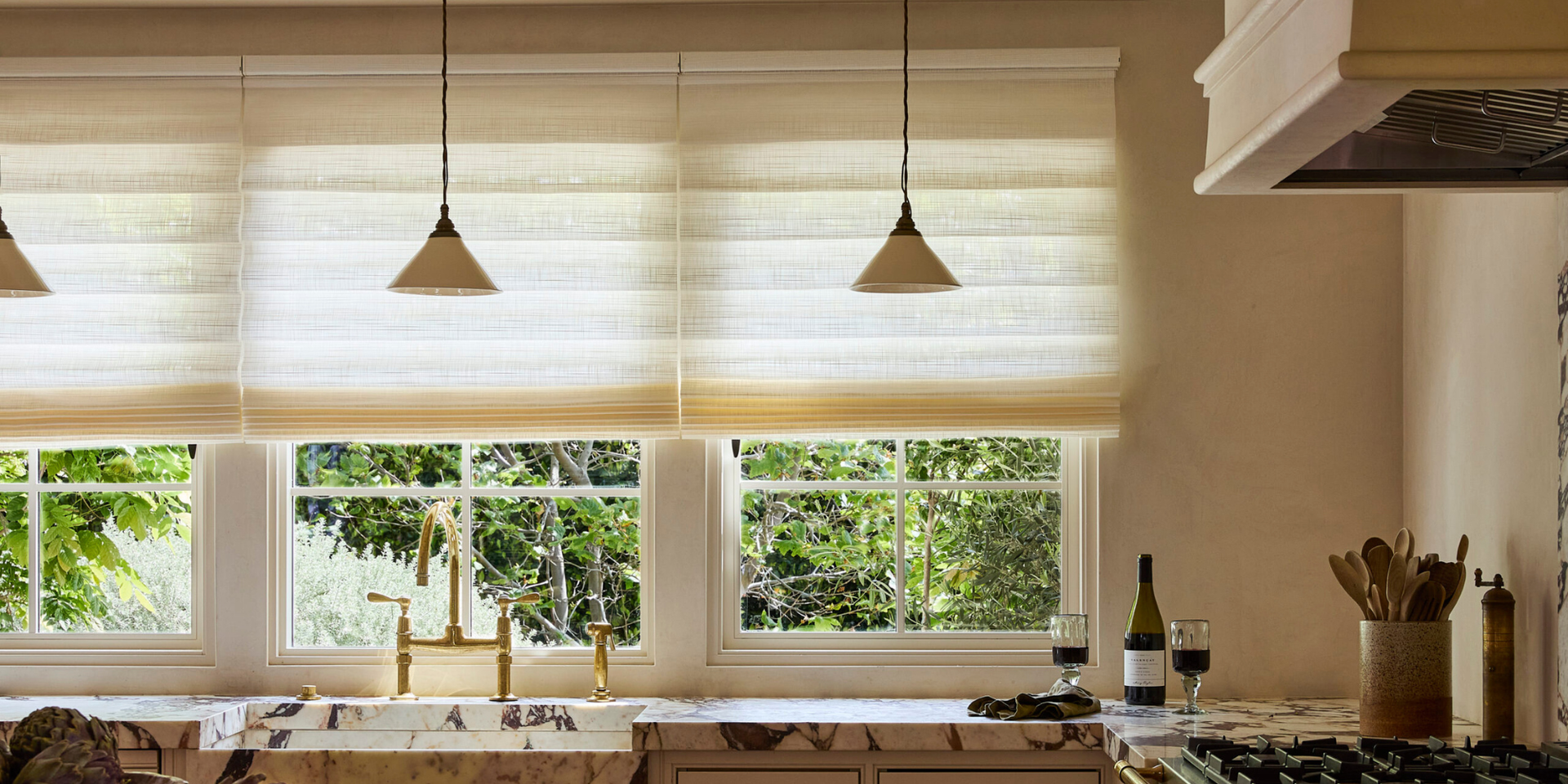 Outside-mount Roman shades on three windows, overlooking greenery outdoors, in a cozy kitchen
