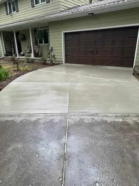 A concrete driveway in front of a house with a garage door.