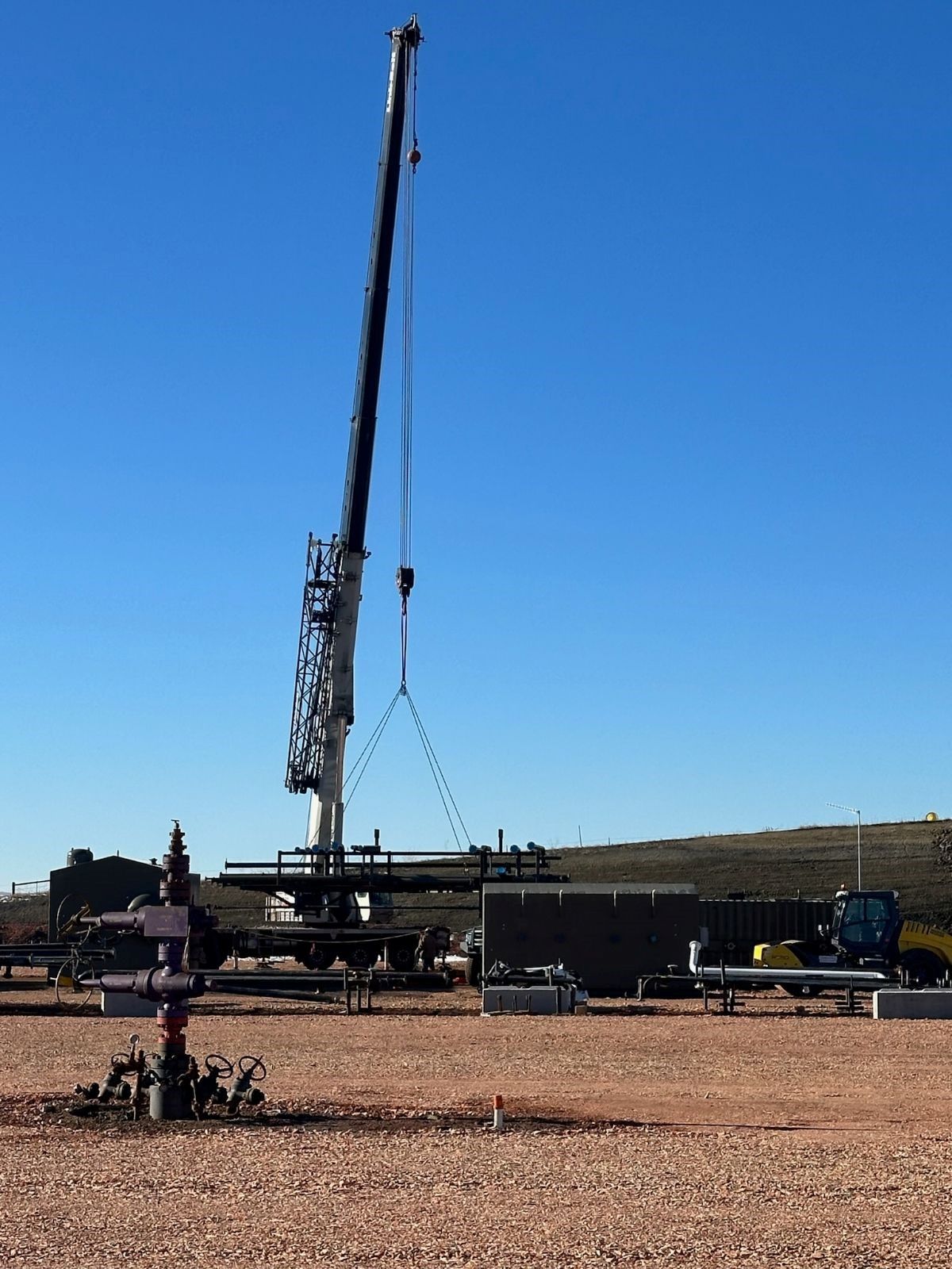A large crane is lifting something in a field