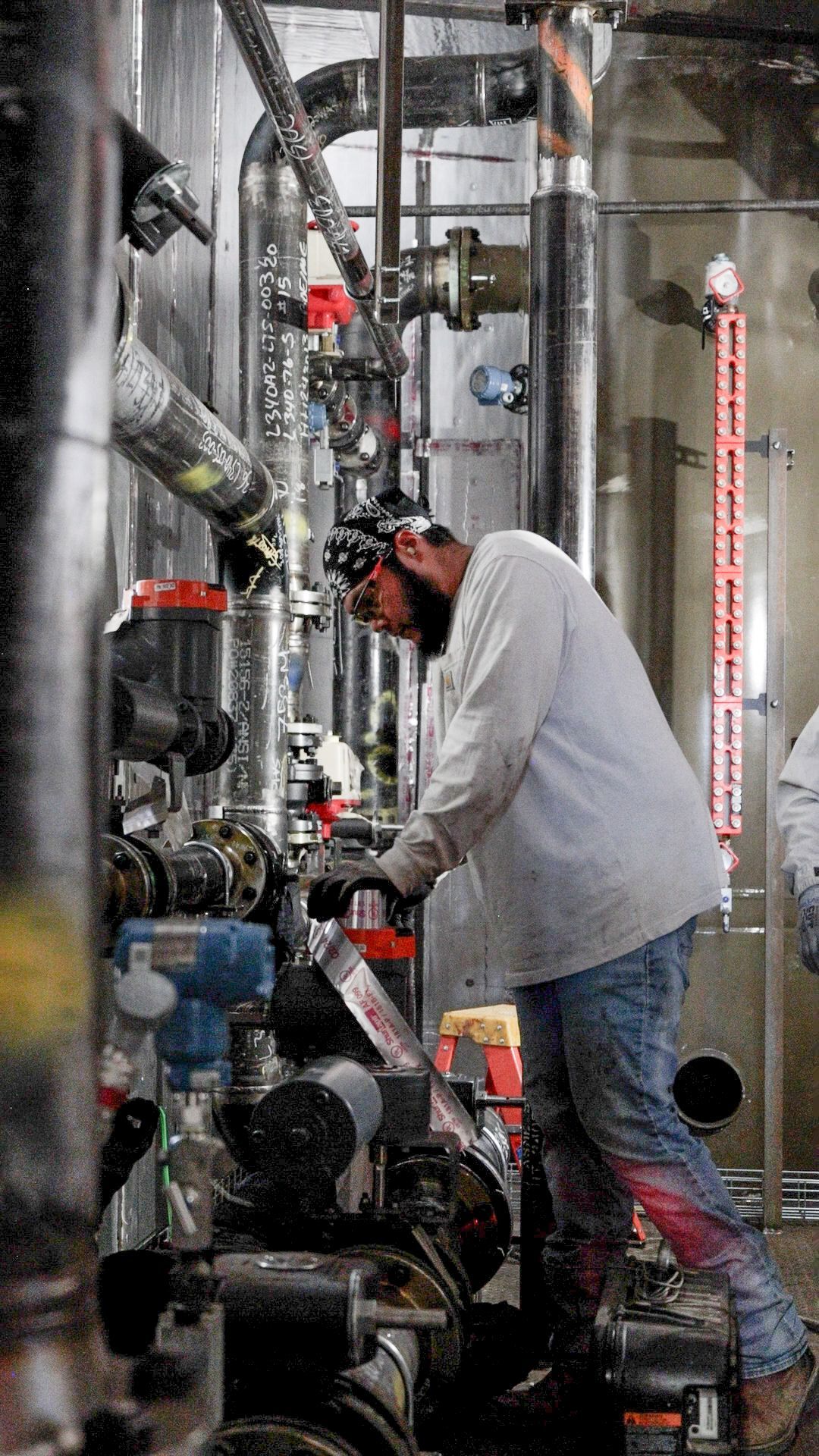 a bunch of pipes in a factory with one that says ' stainless steel ' on it