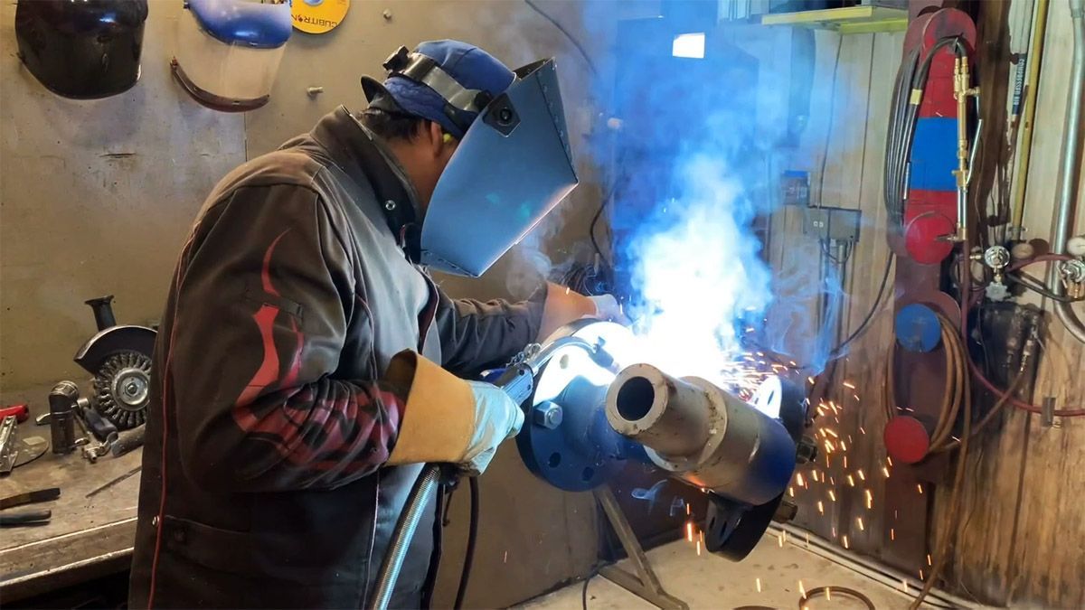 a Pesco employee wearing a welding mask is welding a pipe