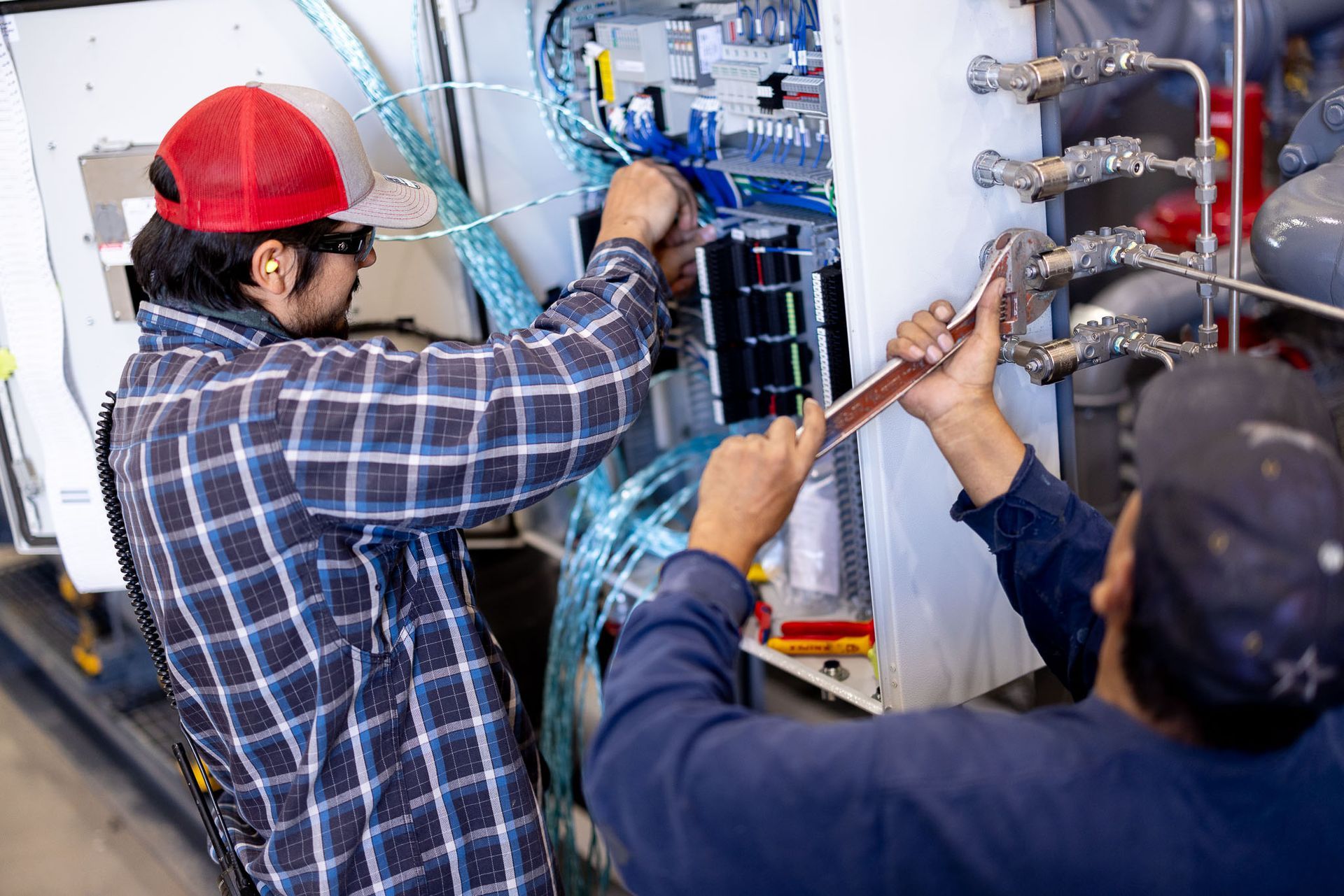 a PESCO employee wearing a hat and ear buds is working on a pipe