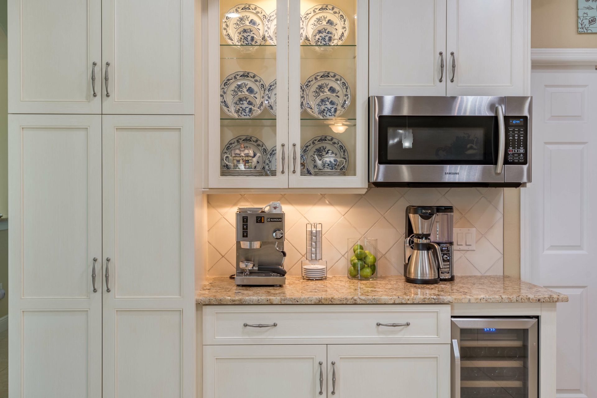 Bright kitchen counter with coffee maker, microwave, and decorative cabinets