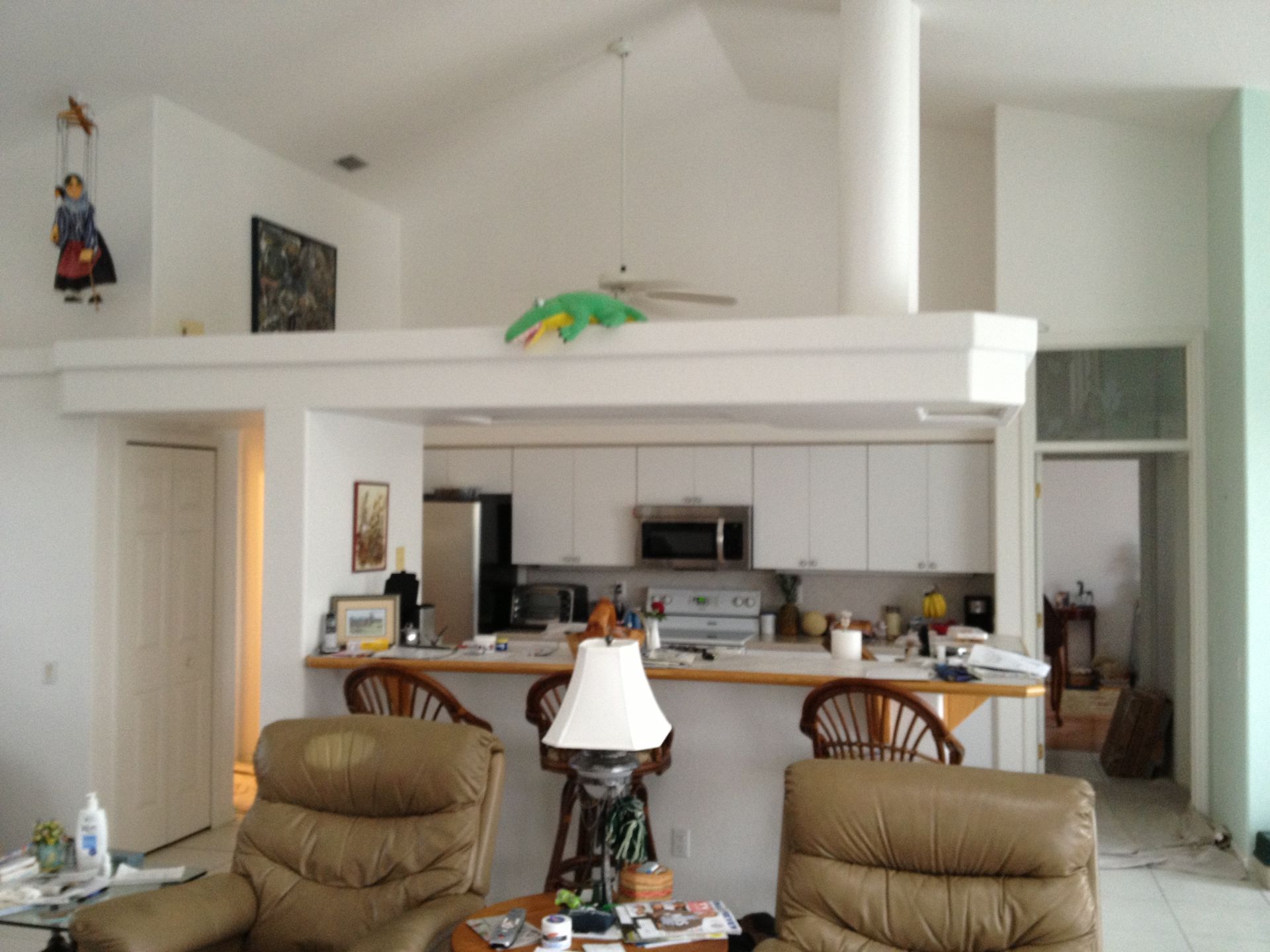 Living room with bar counter, kitchen in back, and two tan recliners in foreground