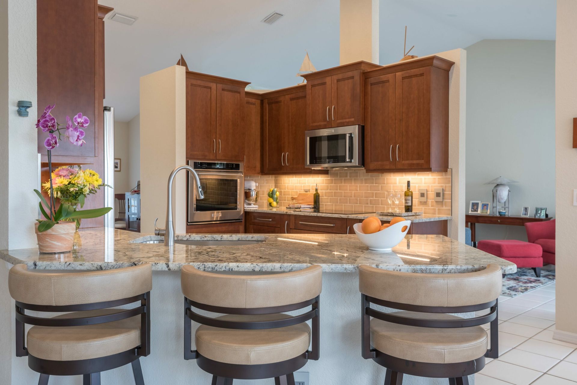Modern kitchen with granite island, wooden cabinets, stainless appliances, and pink flowers by the sink