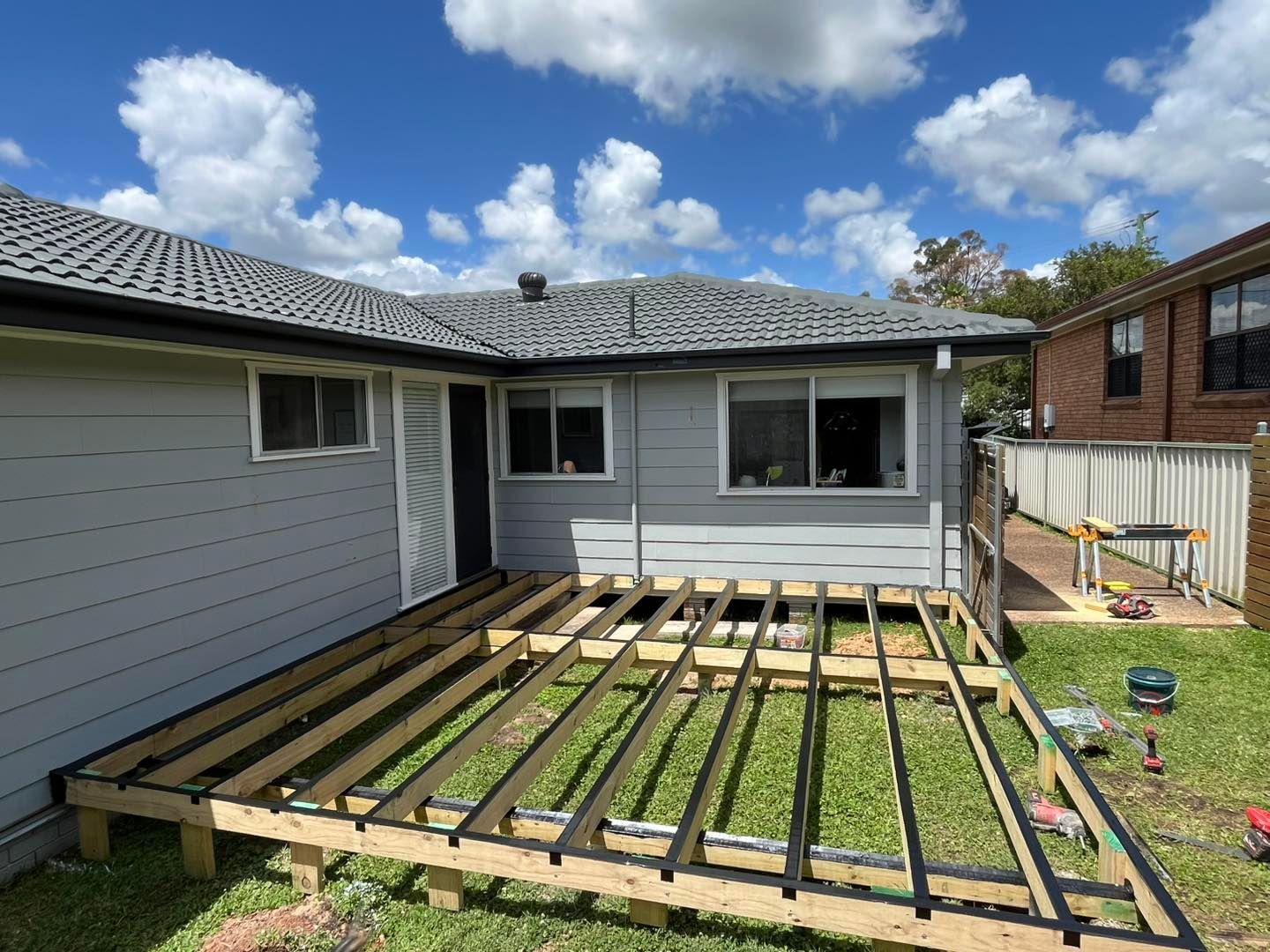 A Man is Working on the Roof of a Building — TM Built Construction In Lochinvar, NSW