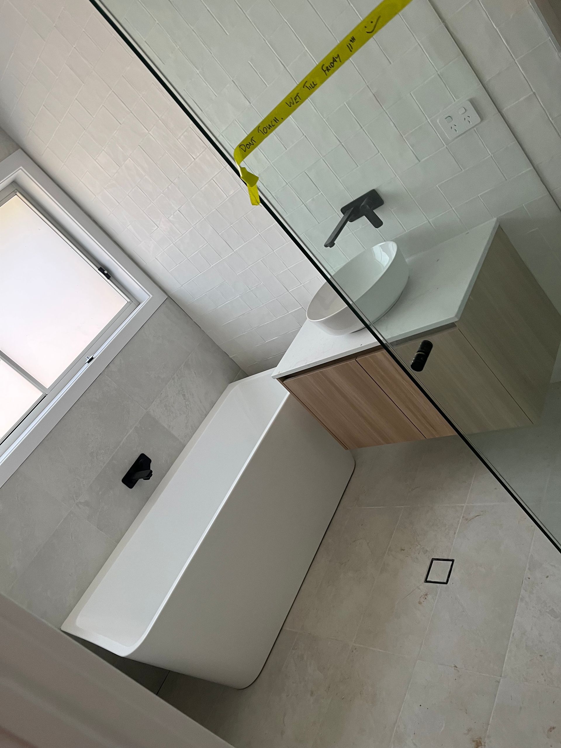 A bathroom with a bathtub a sink and a window — TM Built Construction In Lochinvar, NSW