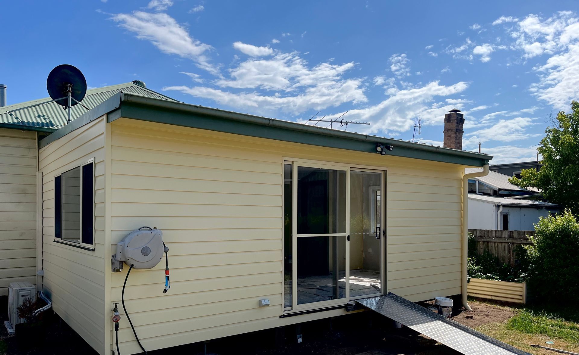 A small house with a ramp and a satellite dish on the roof — TM Built Construction In Lochinvar, NSW