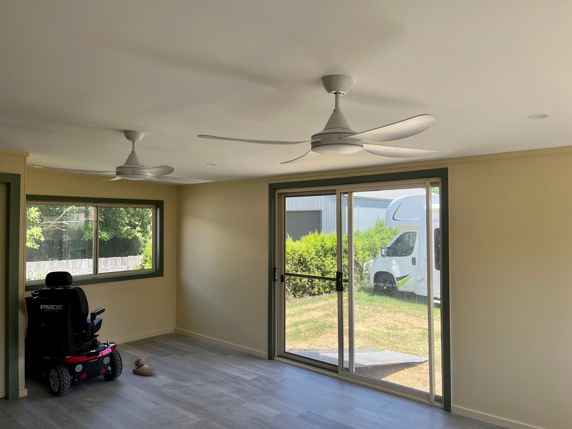 A living room with a ceiling fan and a sliding glass door — TM Built Construction In Lochinvar, NSW